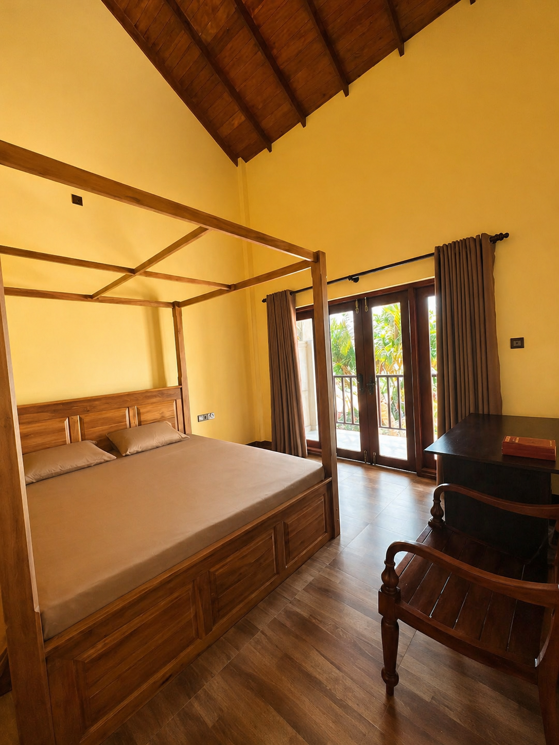 CocoBaru bedroom with wooden canopy bed, desk and balcony doors