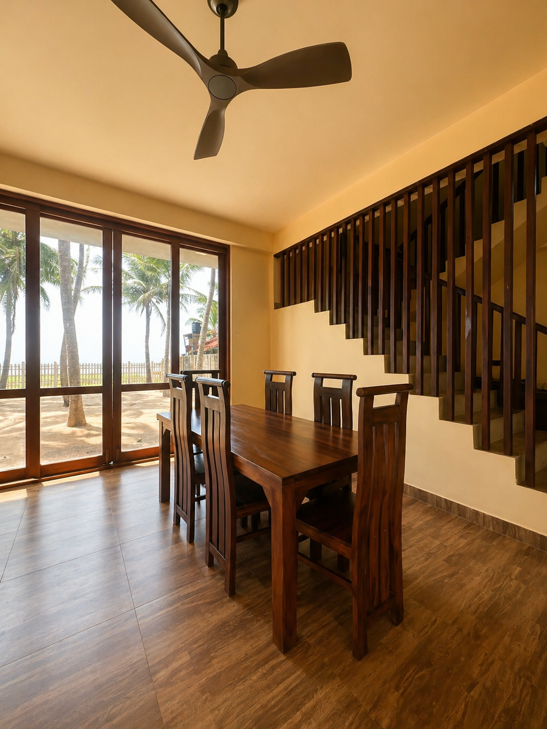 Dining area with timber table and beach view through glass doors